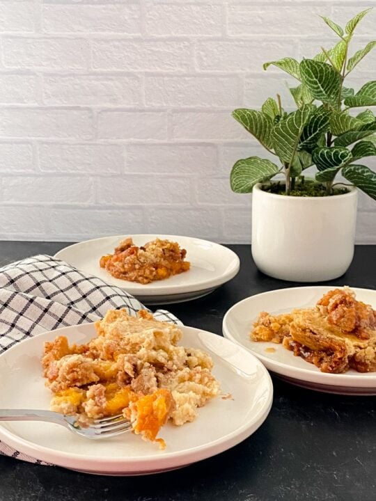 final shot cake mix peach cobbler plated on three plates with plant in background