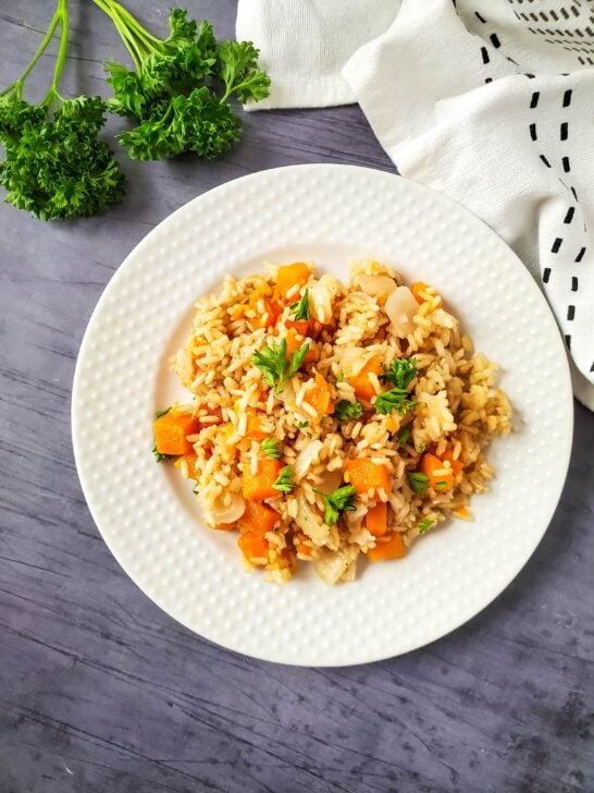 plated slow cooker butternut squash risotto on white plate with tea towel and parsley